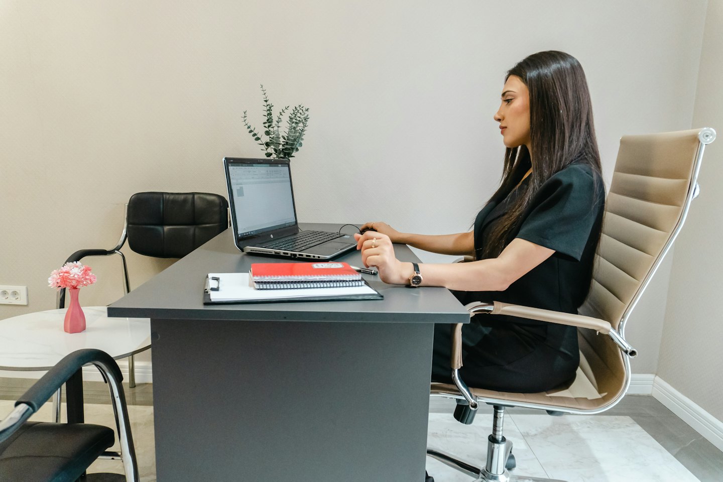 Kobieta pracująca na laptopie przy nowoczesnym biurku.