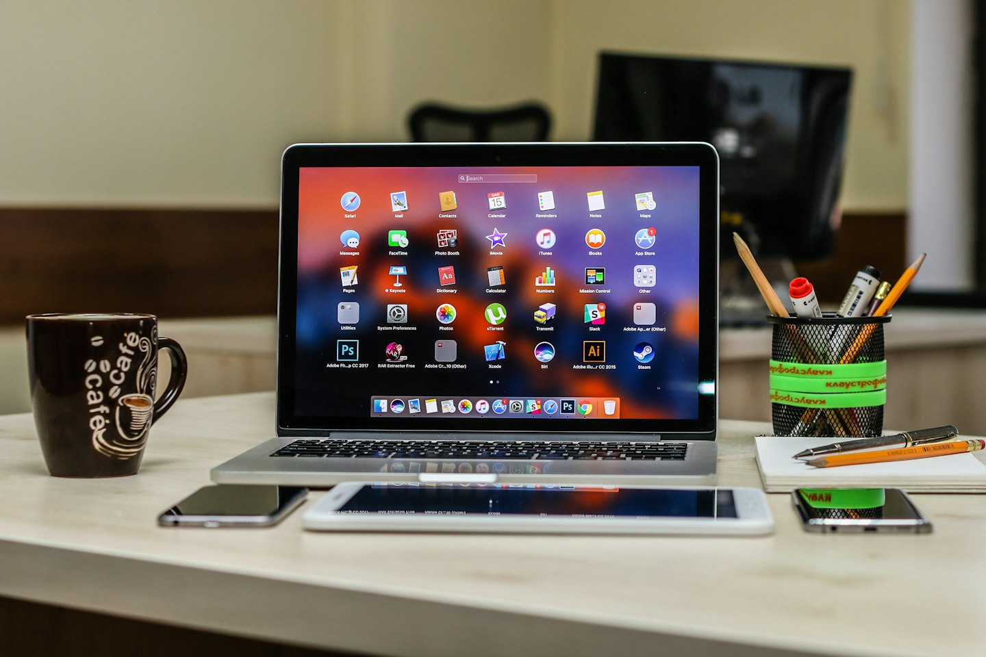 Laptop, tablet i smartfony ułożone na drewnianym biurku.